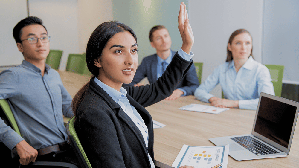 Woman in meeting, raising her hand, which helps make meetings more accessible