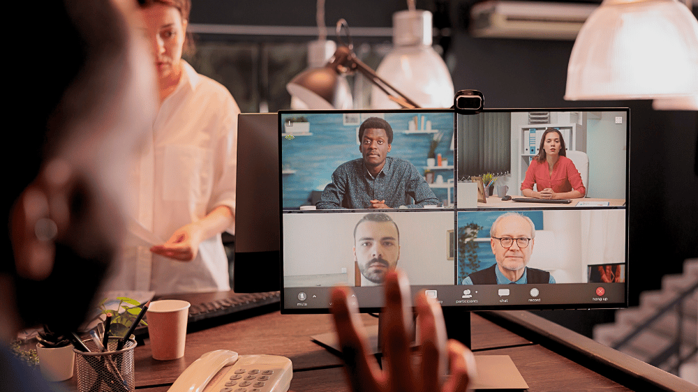 Male in a virtual meeting on his laptop while workers work around him.