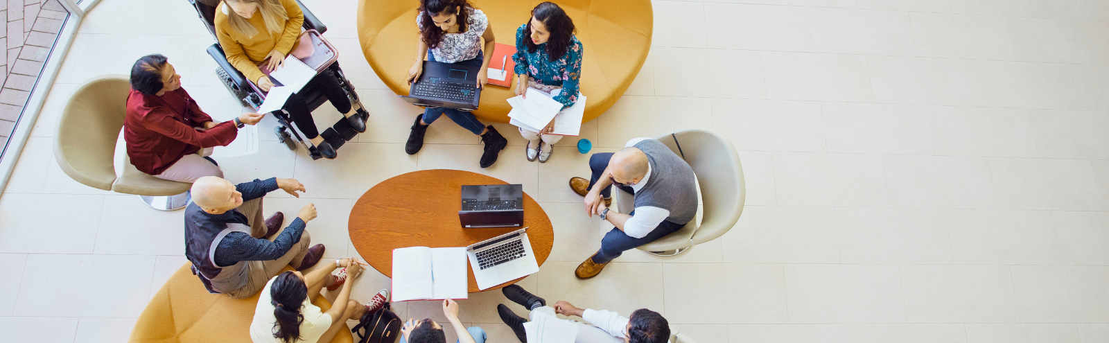 Overhead view of diverse professionals collaborating at a round table in a modern workspace, sharing ideas and exemplifying facilitative leadership and team collaboration