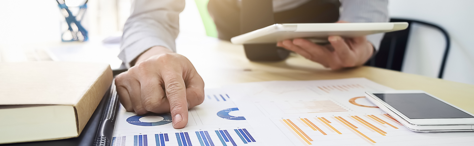 Business professional analyzing ROI data charts with finger pointing at blue graph metrics while holding tablet, demonstrating effective meetings and preparation.